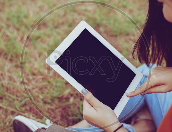 Beauty Asian Woman Using Tablet At Park. People And Technology Concept. Leisure And Outdoor Activity Theme.