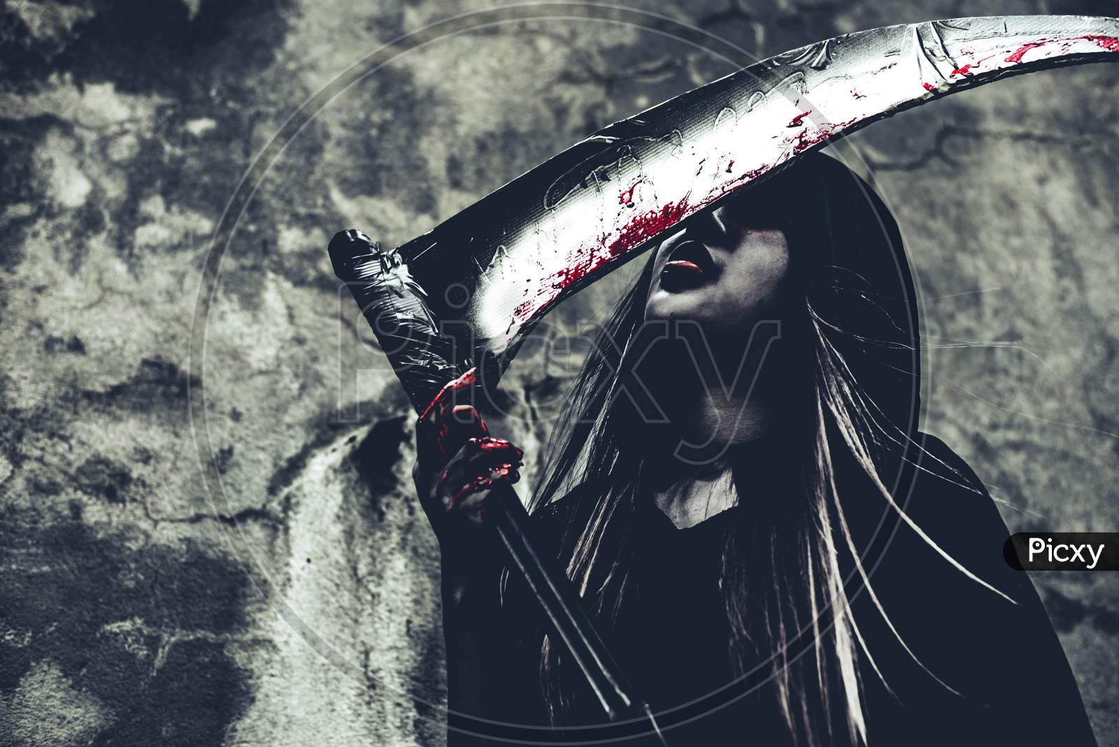 Witch Licking Blood On Reaper. Female Demon Angel In Black Clothes And Hood On Grunge Wall Background. Halloween Day And Mystery Concept. Fantasy Of Magic Theme. Afterlife And Death Concept.