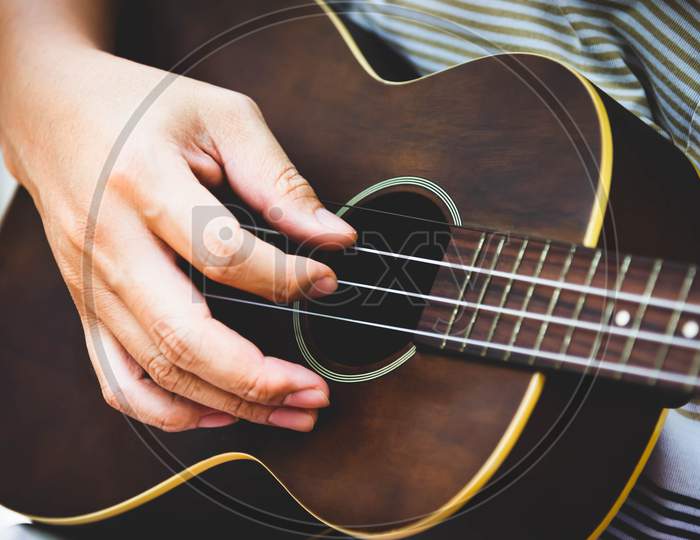 Closeup Of Guitarist Hand Playing Guitar. Musical Instrument Concept. Outdoors And Leisure Theme. Selective Focus On Left Hand. Vintage Country Folk Guitar With Music Singer. Close Up Entertainer Hand