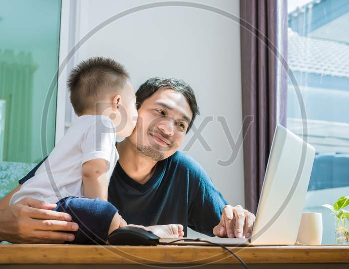 Son Kissing His Father While Using Internet. People And Lifestyles Concept. Technology And Happy Family Theme. Single Dad Theme.