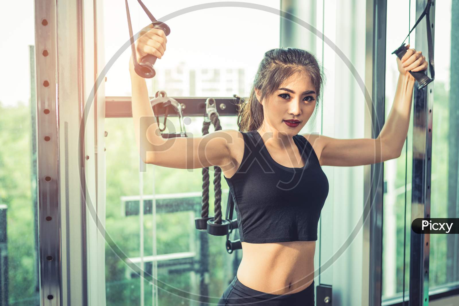 Asian Young Woman Doing Elastic Rope Exercises At Cross Fitness Gym. Strength Training And Muscular Beauty And Healthy Concept. Sport Equipment And Sport Club Center Theme.