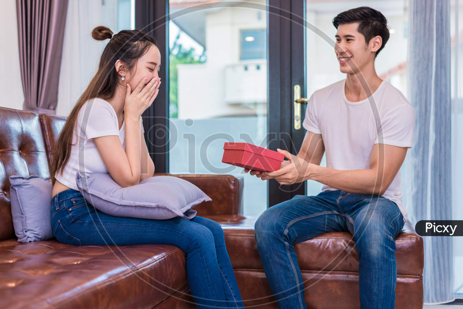 Boyfriend Surprising Girlfriend With Present. Woman Surprised When Looking At Gift Box On Special Day. Lovers And Couples Concept. Honeymoon And Dating Theme. Happiness And Valentines Day Theme.