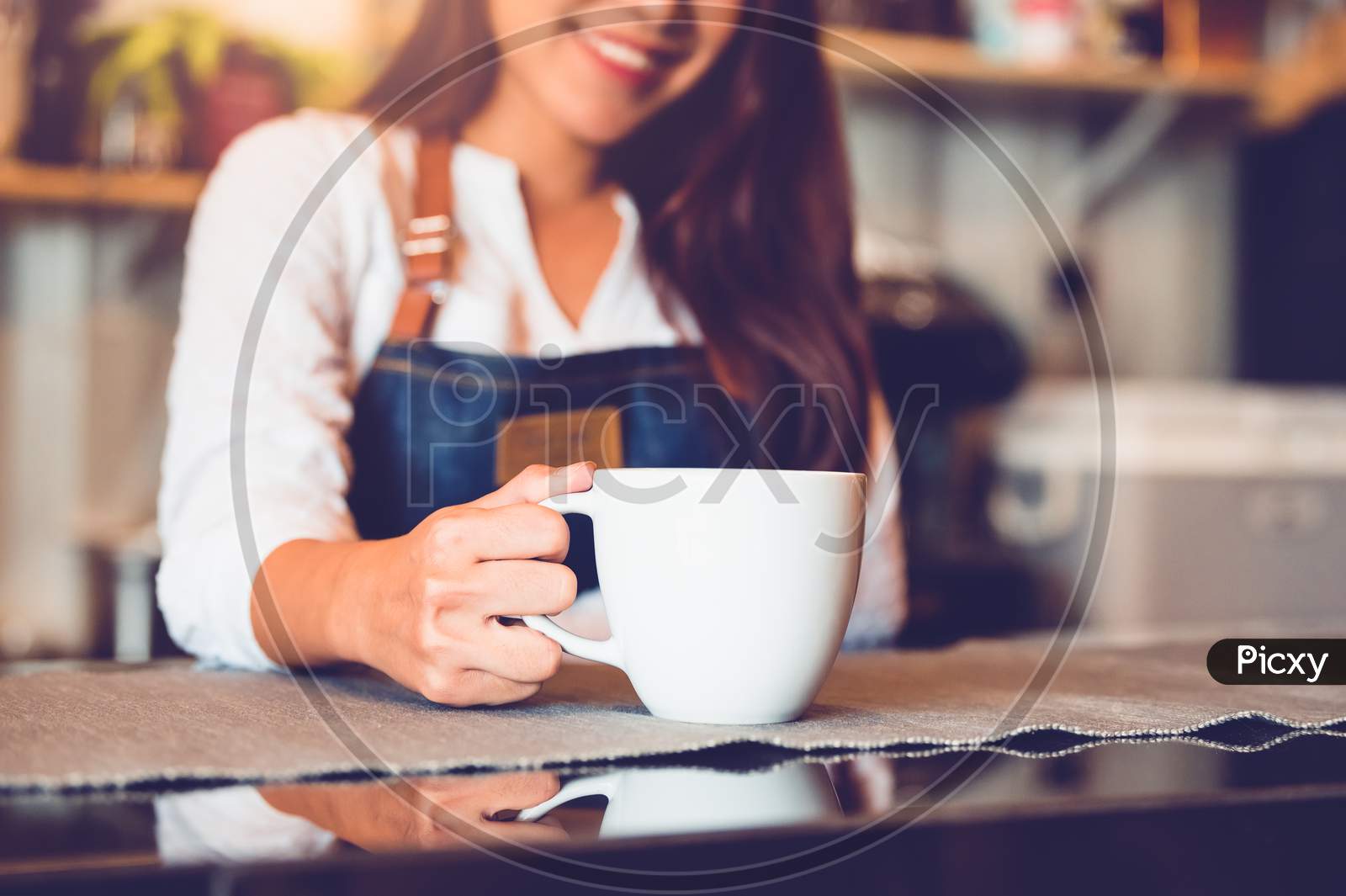 Closeup Of White Coffee Cup With Beautiful Asian Woman Barista Background For Serving To Customer. Job And Occupation. Food And Drink Beverage. Coffee Shop And Cafe. Business And Restaurant Ownership
