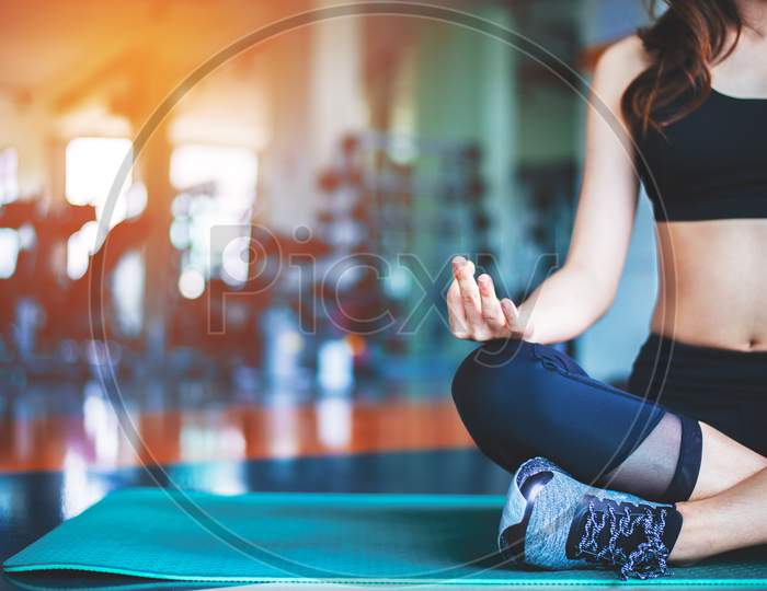 Woman Doing Yoga On Mat At Fitness Gym. Sport And Exercise Concept. Meditation And Fitness Theme. Selective Focus On Hand