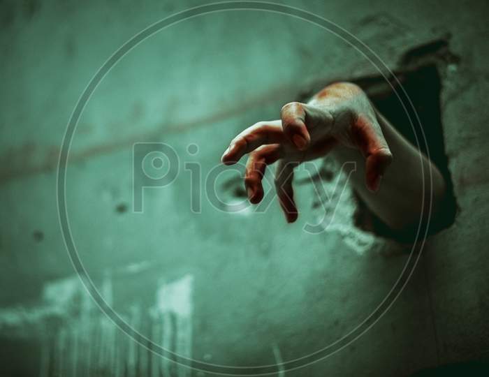 Zombie Hand Through The Cracked Wall. Horror And Scary Film Concept. Halloween Day Theme. Green Tone Like Ghost Movie