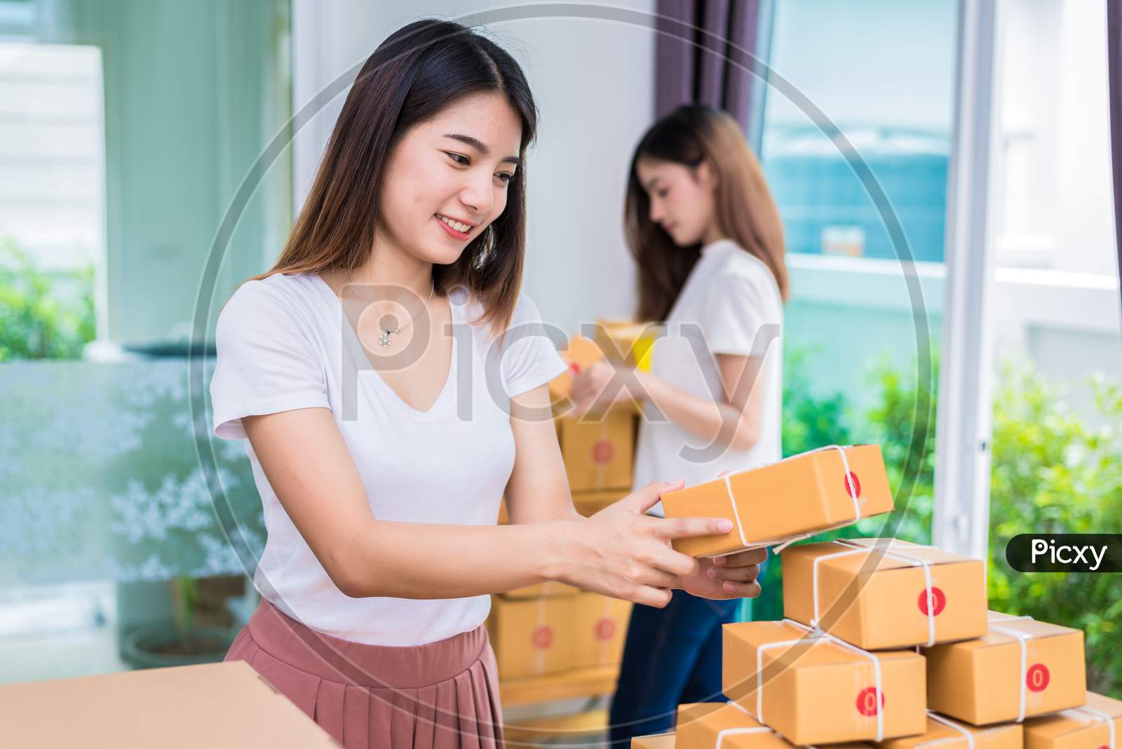 Two Young Asian Girl Freelancers Business Owner Working At Home Office And Sorting Parcel Post Box To Delivery Service To Customer. Packaging Order And Shopping Online Concept.