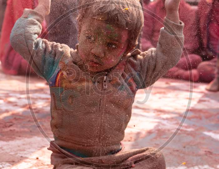 Indian Kid celebrating Colorful Holi festival at Barsana