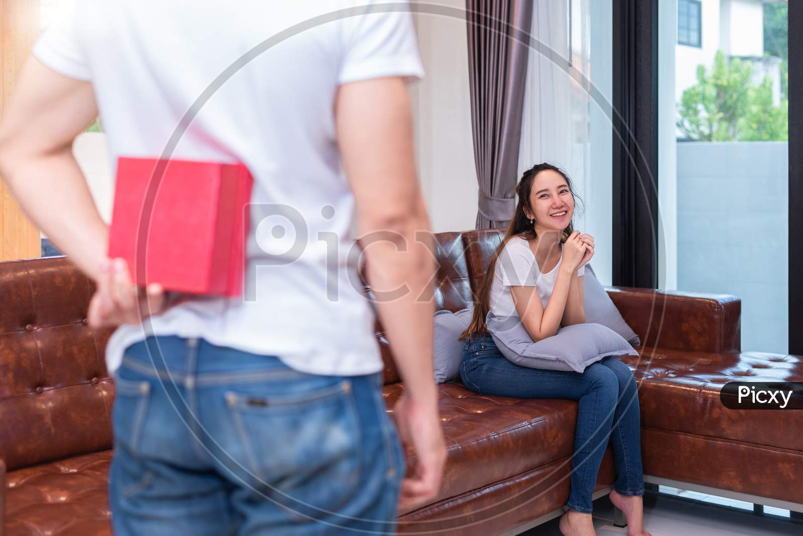 Boy Surprise His Asian Girlfriend By Holding Gift Box Behind Him At Their Home. Valentine'S Day And Pre Wedding Honeymoon Concept. People And Lifestyles Concept.