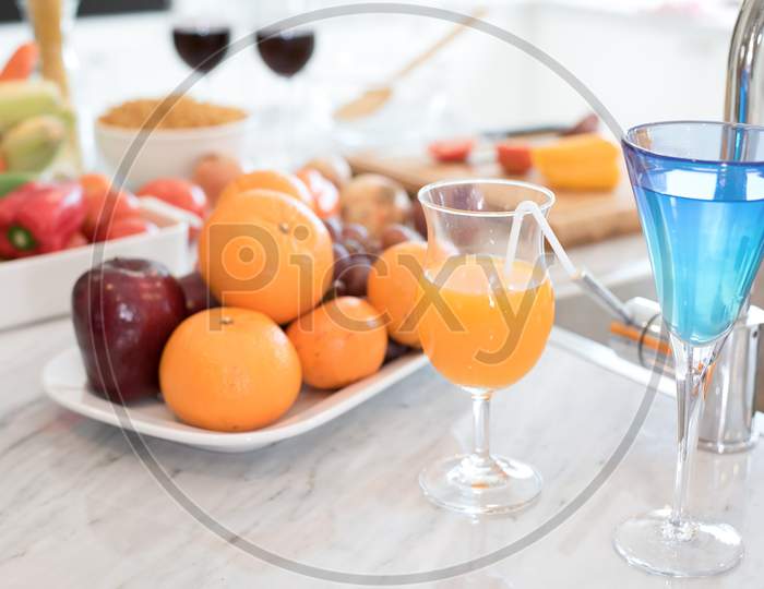 Fruit And Fruit Juice On Marble Counter In Kitchen Room. Apple And Orange Juice And Vegetable On Table. Food And Drinks Concept. Party And Celebration Theme