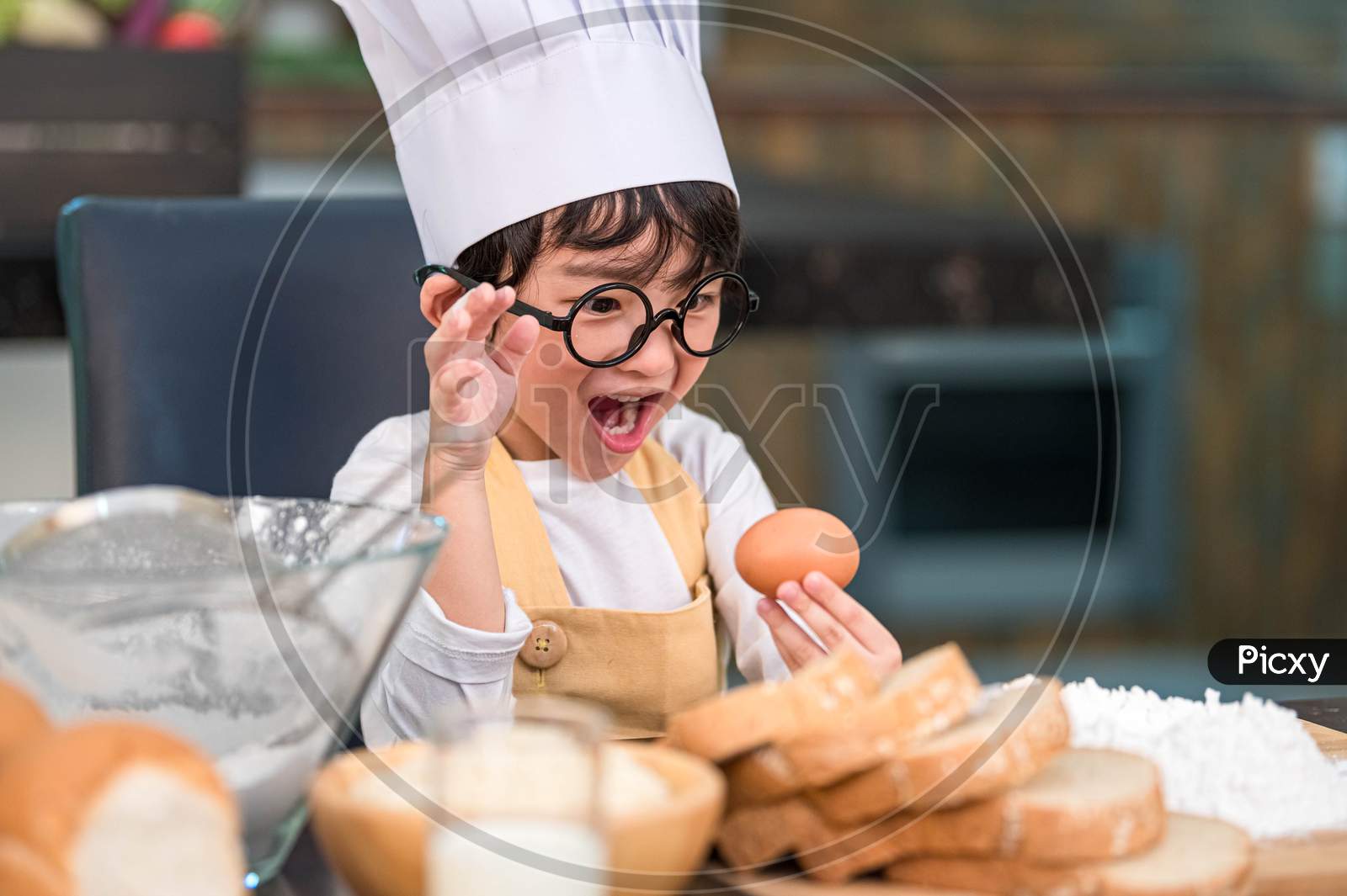 Portrait Cute Little Asian Happy Boy Surprised And Interested In Cooking Funny In Home Kitchen. People Lifestyles And Family. Homemade Food And Ingredients Concept. Baking Christmas Cake And Cookies