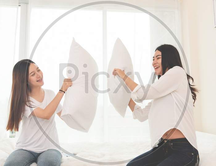 Two Asian Girls Doing Pillow Fight In Bedroom As Childhood. Lifestyles And People Concept. Relation And Friendship Theme. Couple And Friends Concept. Lgbt And People Lifestyle