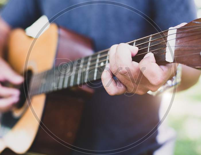 Close Up Of Guitarist Hand Playing Guitar. Musical And Instrument Concept. Outdoors And Leisure Theme. Selective Focus On Left Hand.