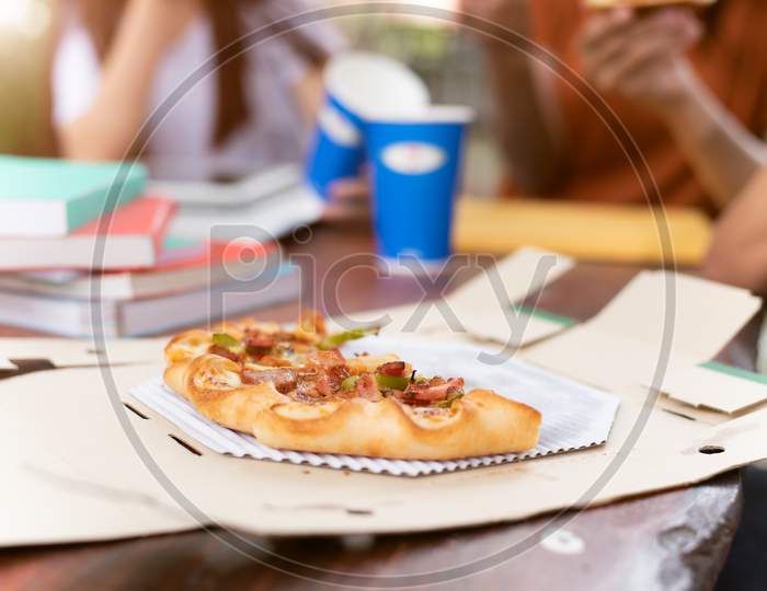 Pizza In Delivery Box With People Friendships Party Background. Pizza Sliced Pieces On Outdoor Table Classroom Celebrate By College Student After Examination. Pizza With Cheese And Sausage Fast Food