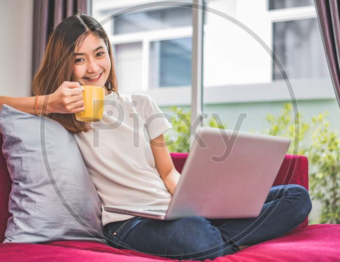 Asian Woman Enjoy Herself While Using  Internet On Laptop And Phone In Office. Business And Marketing And Part Time Concept. Online Shopping And Business Success Theme. Happy Mood Doing Working Job.