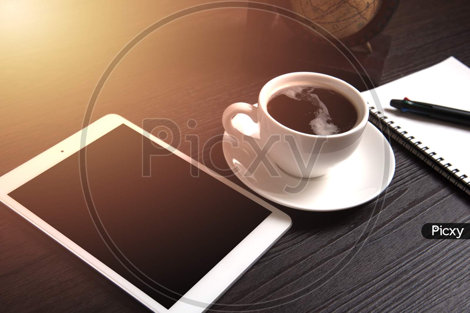 Tablet And Black Coffee On Wooden Table With Digital Earth World Map And Orange Light And Line Dot, Notebook And Pen, Technology Concept, Drinking And Relax Concept, Coffee Break Time Concept