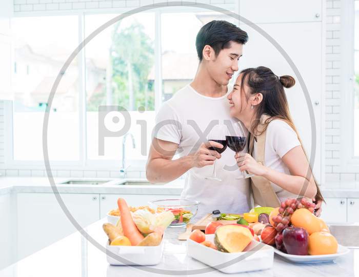Asian Lovers Or Couples Drinking Wine In Kitchen Room At Home. Love And Happiness Concept Sweet Honeymoon And Valentine Day Theme