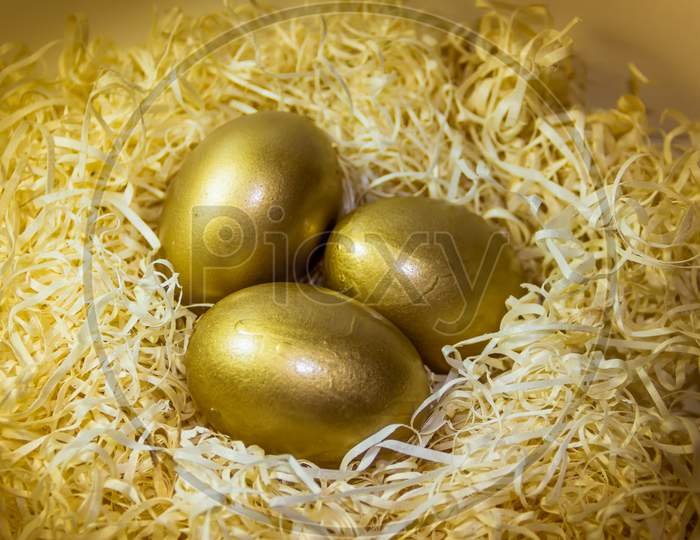 Golden Easter Eggs In Straw Nest With Rustic Wooden Background