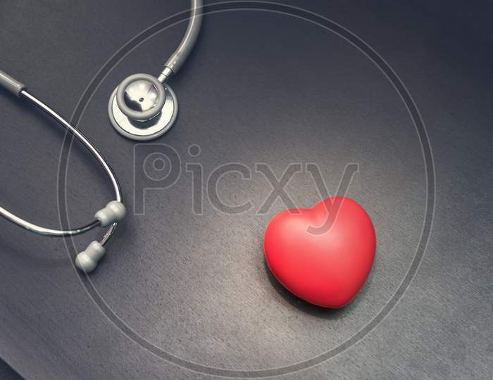 In Top View, Red Heart With Stethoscope Medical Equipment On The Doctor Desk Background. Medical And Health Care Concept, Hospital And Emergency Theme, Dark Tone Pinterest And Instragram Like Process.