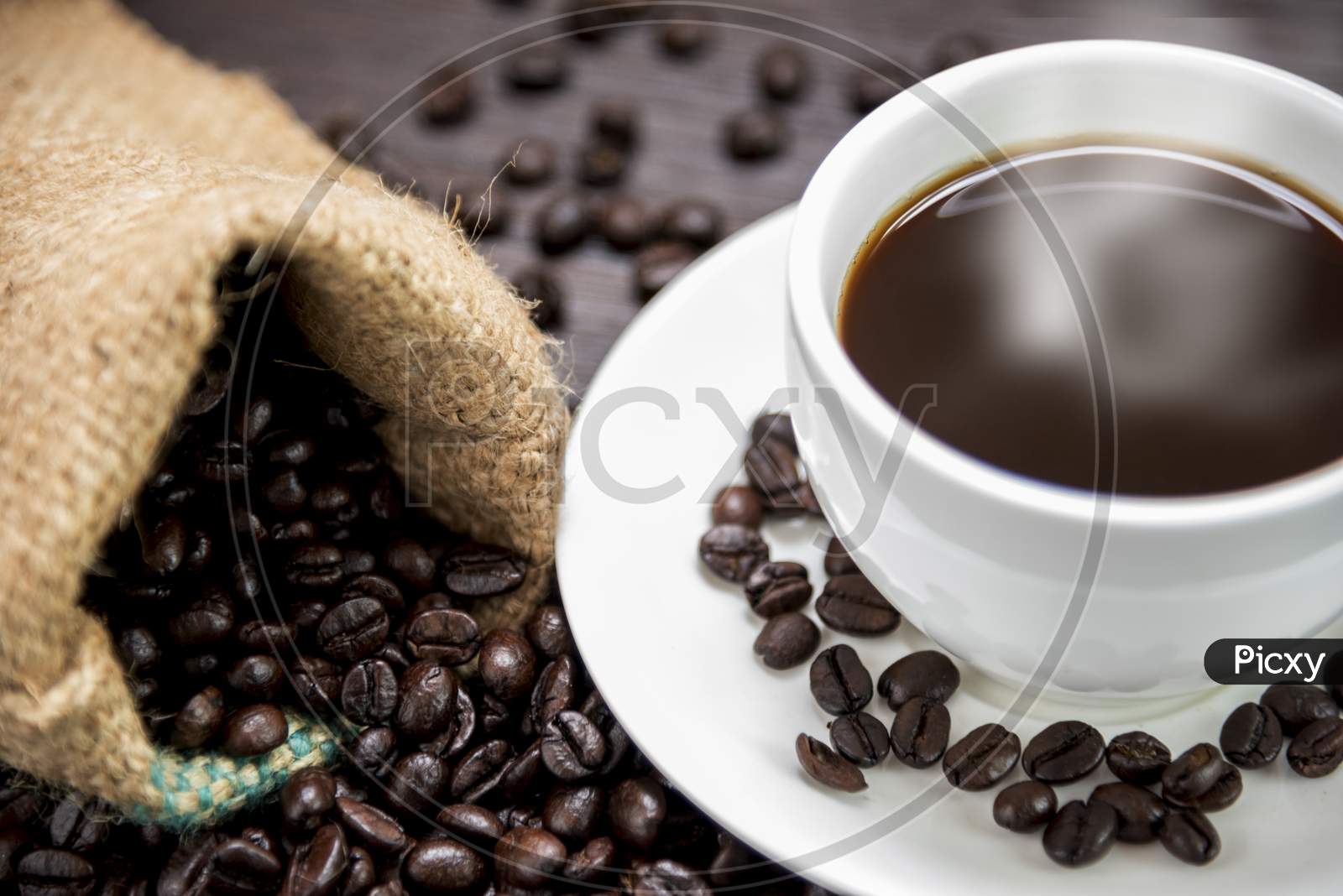 Coffee Cup With  Smoke And Coffee Beans In Sack On Wood Table, Drinks And Relax Concept, For Advertising