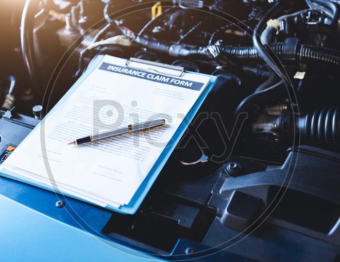 Clipboard On Car With Car Insurance Claim Form For Customer Maintenance Vehicle Checklist In Auto Repair Shop Garage. Engine Repair Service Concept. Business Technical Mechanics Support For Fixing Car
