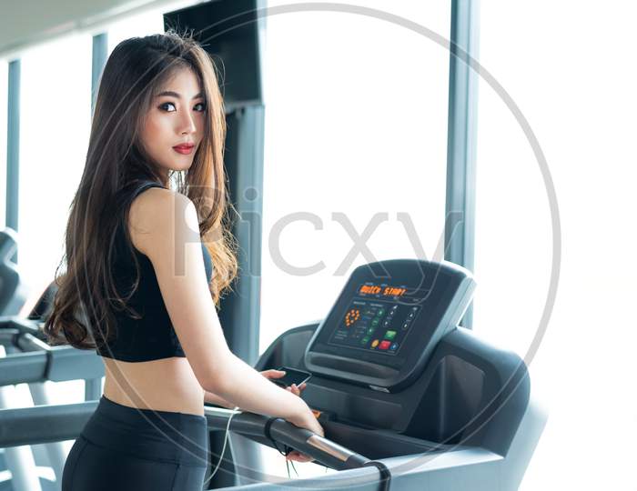 Asian Sport Woman Walking Or Running On Treadmill Equipment In Fitness Workout Gym. Sport And Beauty Concept. Workout And Strength Training Theme. Cardio And Diet Theme. Woman Portrait