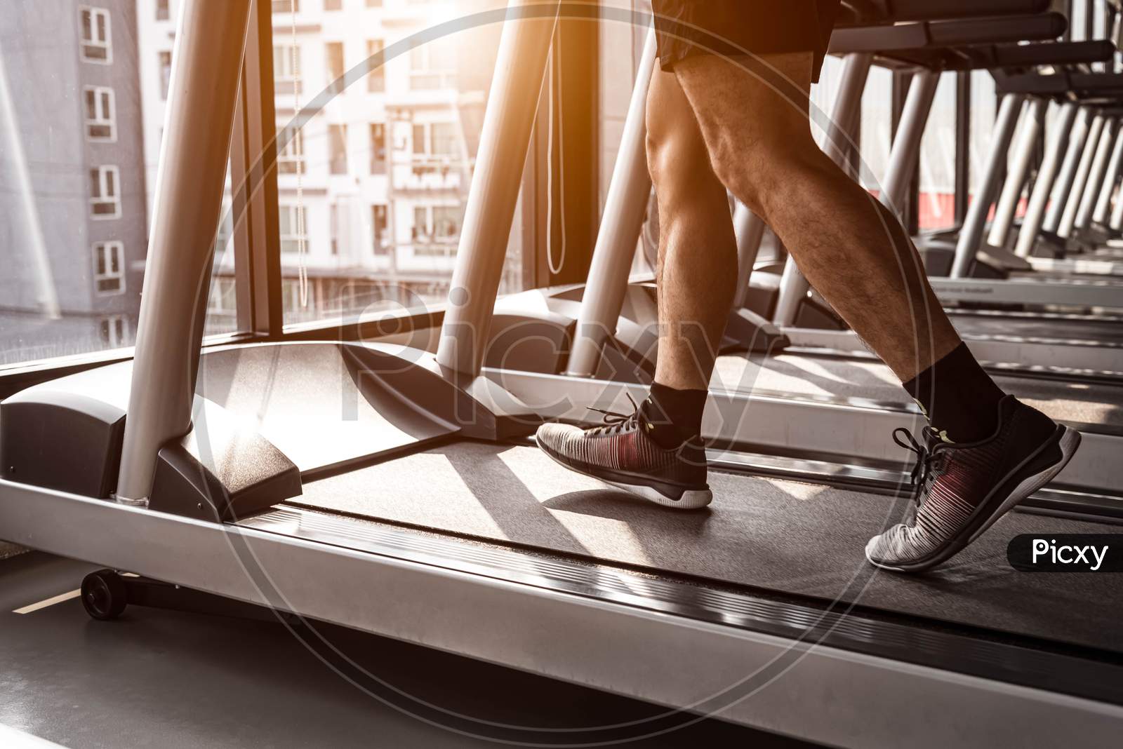 Close Up Of Sport Man Running On Treadmill In Fitness Gym At Condominium In Urban. People Lifestyles And Sport Activity Concept.
