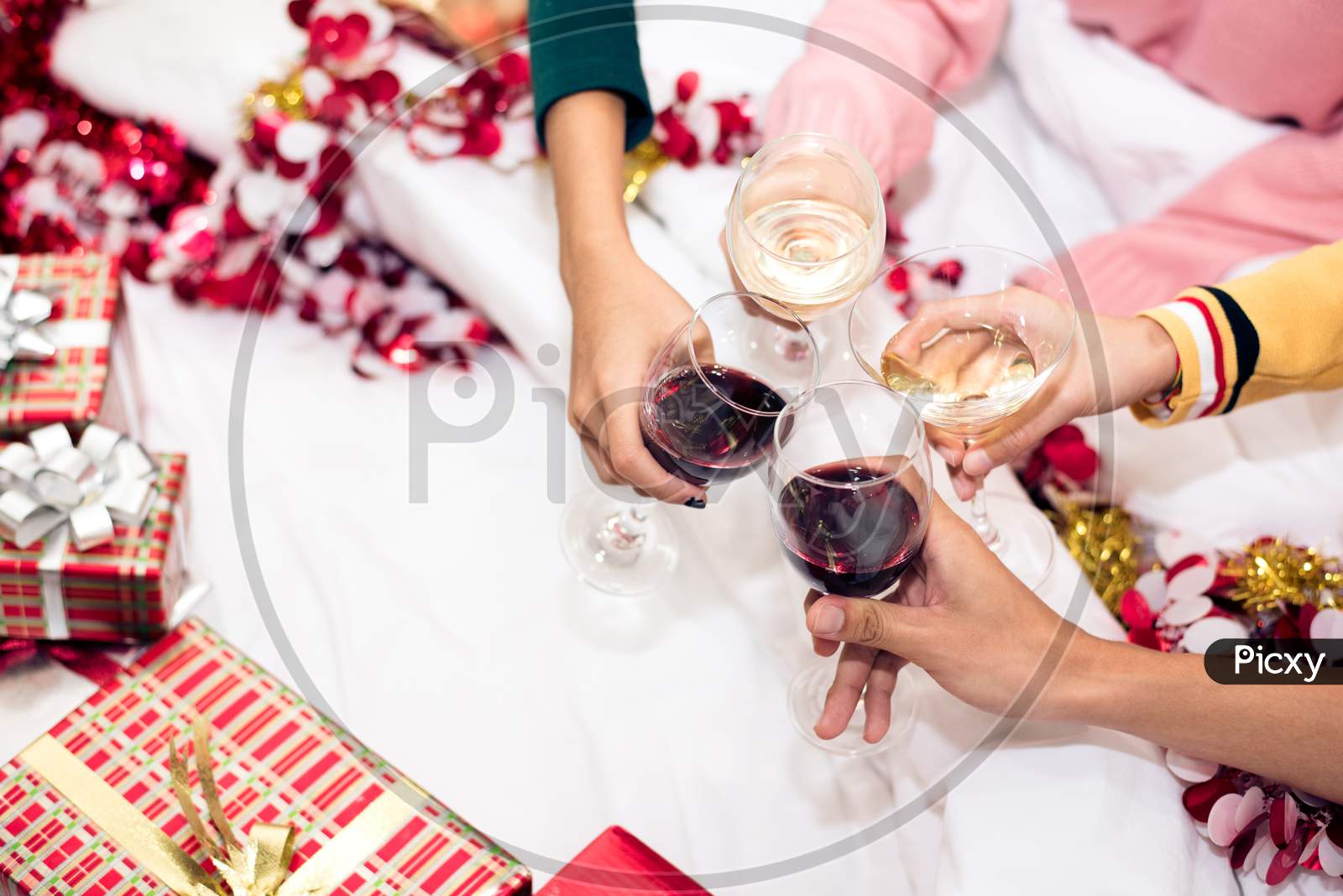 Hands Of People Celebrating New Year Party In Home With Wine Drinking Glasses. New Year And Christmas Party Concept. Happiness And Friendship Concept. Relation And Funny Together Theme. Clinking Glass