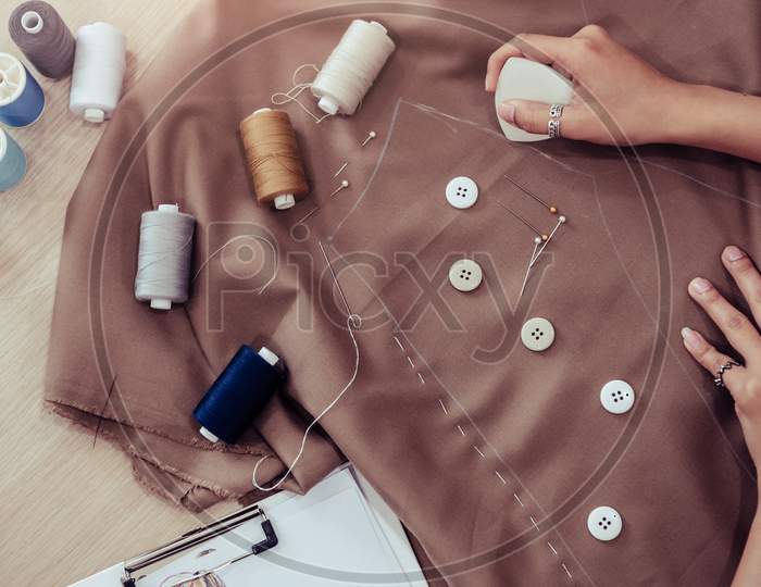 Top View Of Beautiful Dressmaker Sewing Dress Fabric With Hand. Fashion Designer Tailor Or Sewer In Workshop Studio Designing New Collection Clothes. Business Owner Shop And Entrepreneur Concept.