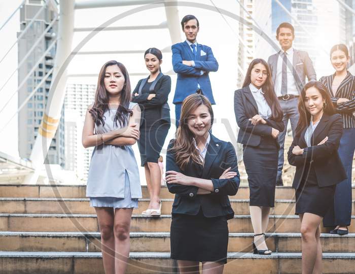 Portrait Of Successful Group Of Business People At Outdoor Urban. Happy Businessmen And Businesswomen Standing As Team In Satisfaction Gesture. Successful Group Of People Smiling And Looking At Camera