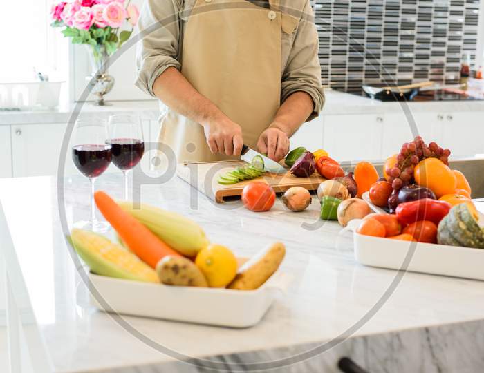 Man Cooking And Slicing Vegetable In The Kitchen. People And Lifestyles Concept. Food And Drink Theme.