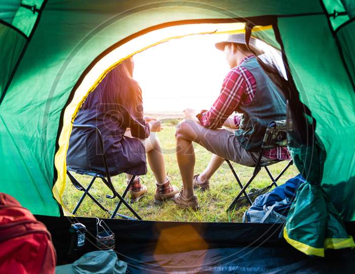 Male And Female Campers Talking Each Others In Front Of Camping Tent. People And Lifestyles Concept. Picnic And Travel Concept. Nature In Summer Theme. Back View And Inside Of Tent Angle