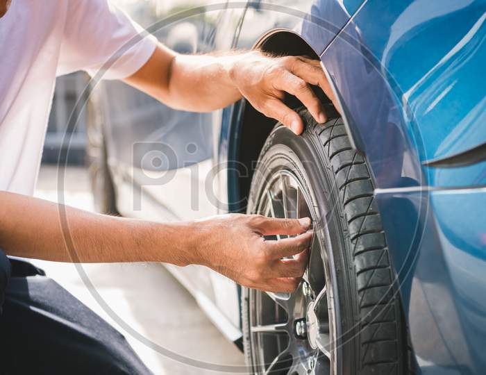 Closeup Male Automotive Technician Removing Tire Valve Nitrogen Cap For Tire Inflation Service At Garage Or Gas Station. Car Annual Maintenance And Repair Concept. Safety Road Trip And Travel Theme.