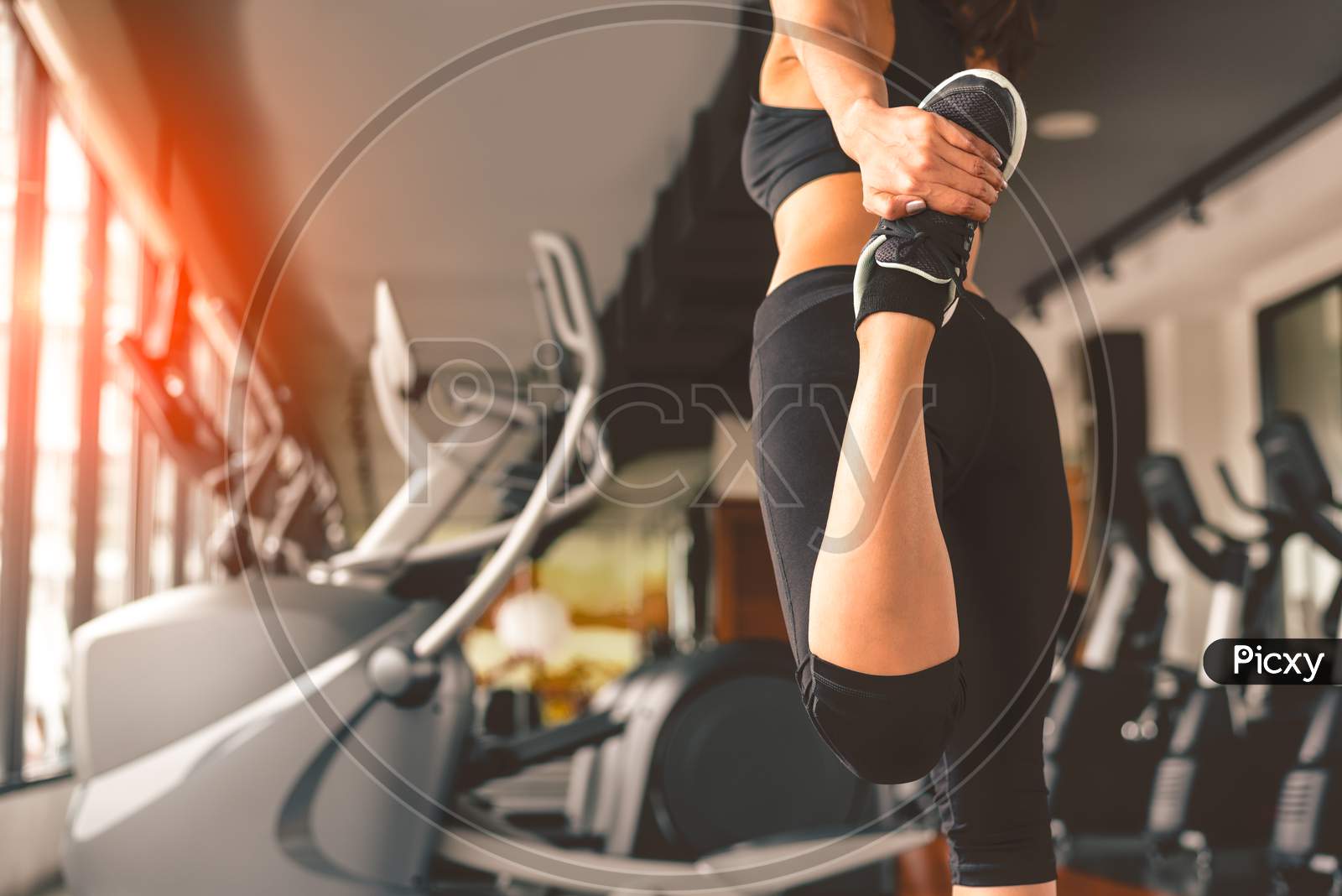 Back View Of Woman Doing Yoga In Fitness Sport Training Club With Sport Equipment And Accessories. Workout And Bodybuilder Concept. Lifestyles Leisure And Indoors Activity. Treadmill Background