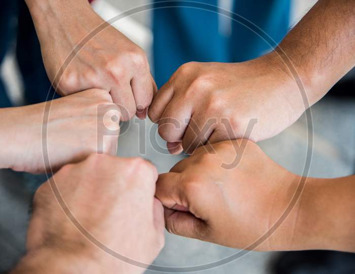 Close Up Top View Of Young People Doing Fist Bump By Hands Together. People And Business Concept. Unity And Teamwork Theme.