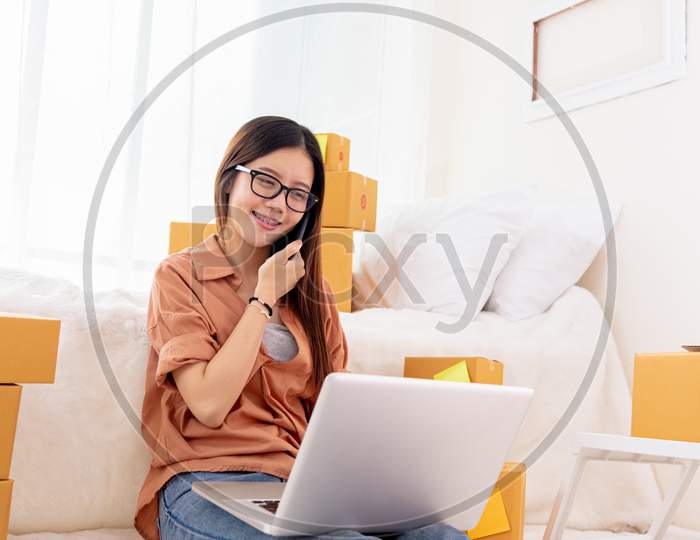 Beauty Asian Woman Using Laptop And Calling Phone On Bed. Business And Technology Concept. Delivery And Online Shopping Concept. Post And Service Theme. People Lifestyle Remote Work In Domestic House