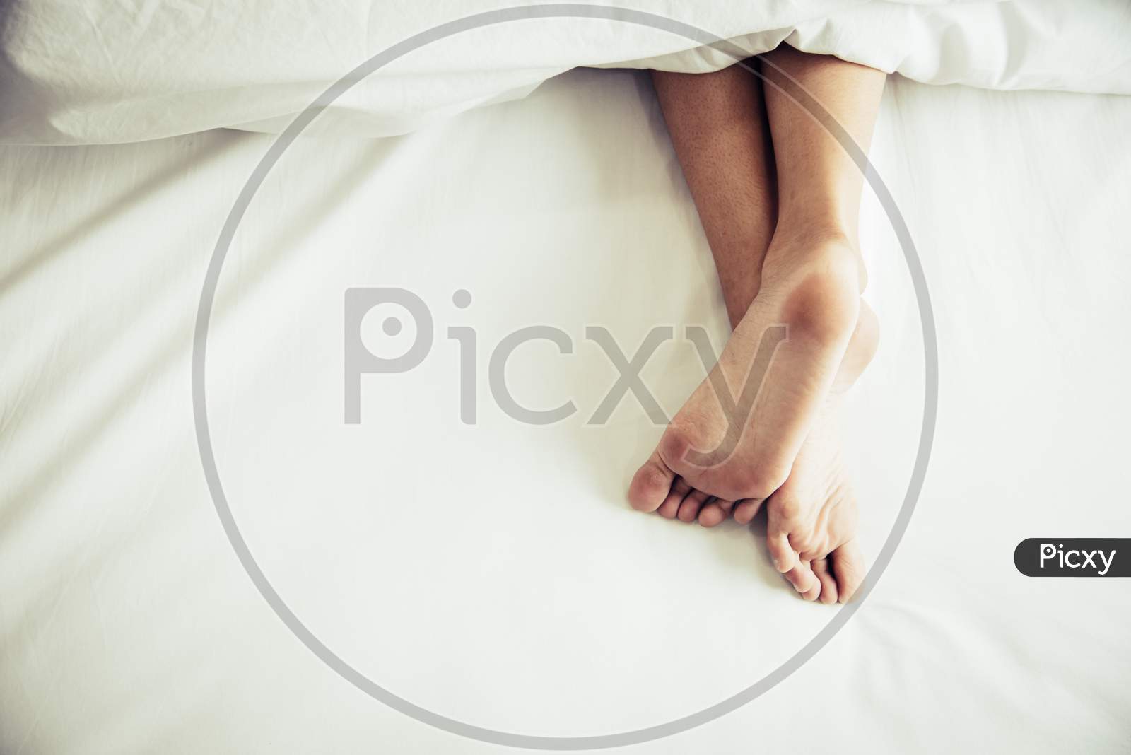 Barefoot Of Human On Bed In Morning. Single And Working People Concept. Lazy Day And Happiness Home Theme.