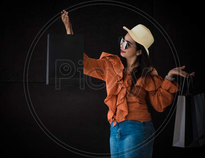 Asian Shopping Woman Enjoy With Black Friday Shopping Bag On Black Background. Shopaholics And Beauty Fashion Theme.