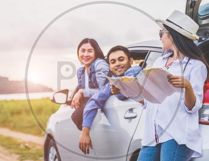 Happy Asian Woman And Her Friends Standing By Car On Coastal Road At Sunset. Young Girl Having Fun During Road Trip. People Lifestyles And Travel Vacation Concept. Friendship Journey And Outdoor Tour