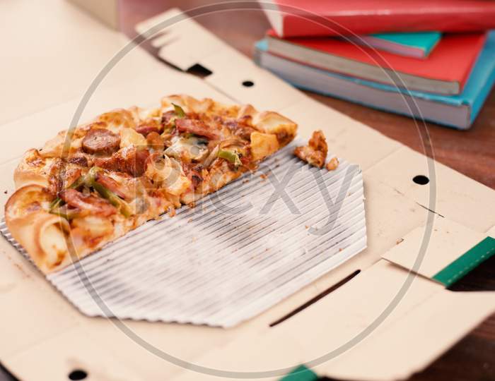 Piece Of Pizza On Table. Pizza On Table With Books And Drinks For Students Who Celebrating Party After Examination. Cut Off Pizza In Delivery Box. Food And Beverage Concept. Park And Outdoors Theme