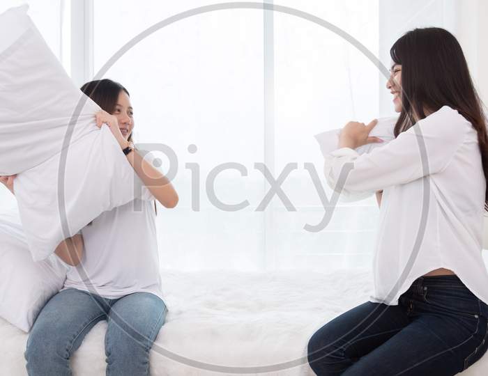 Two Asian Girls Doing Pillow Fight In Bedroom As Childhood. Lifestyles And People Concept. Relation And Friendship Theme. Couple And Friends Concept. Lgbt And People Lifestyle