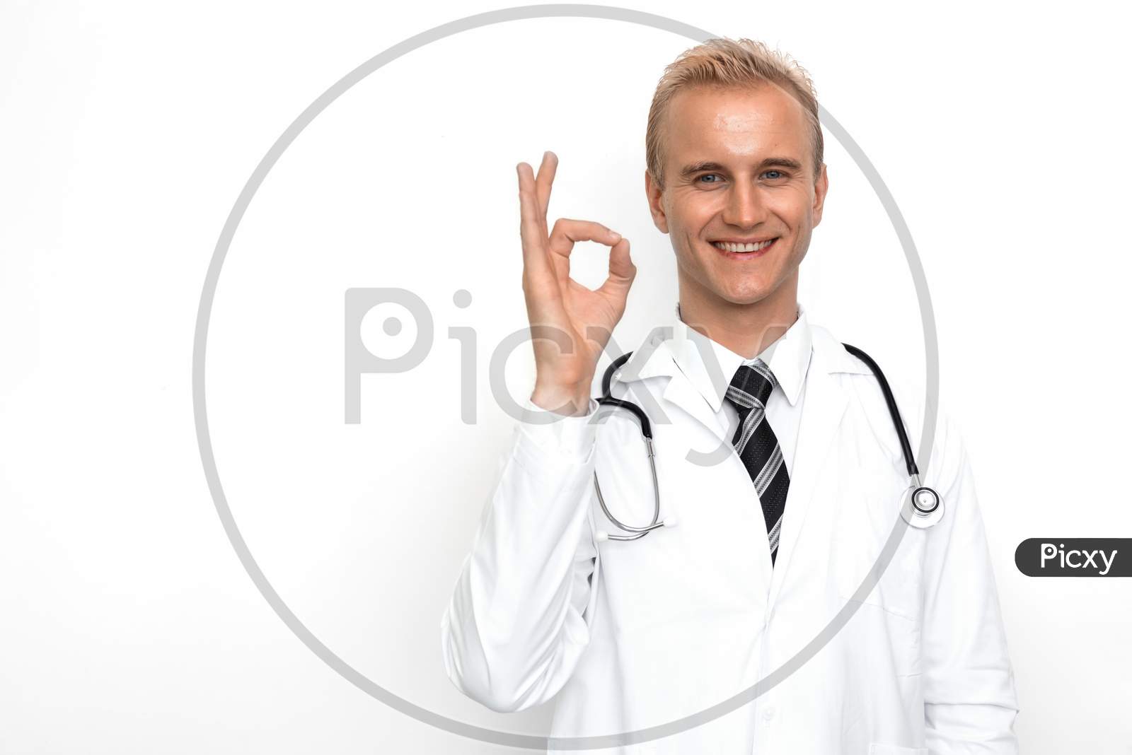 Doctor With Stethoscope Show Off Ok Or All Right Sign By His Hand On The White Background. Medical And Healthcare Concept. Hospital Theme