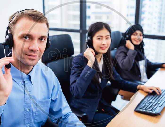 Group Of Young Profession Call Center Operator Agent With Headsets Working In Office. Business Telemarketing Service People Concentrating On Having Conversation Work And Talking To Customer Friendly