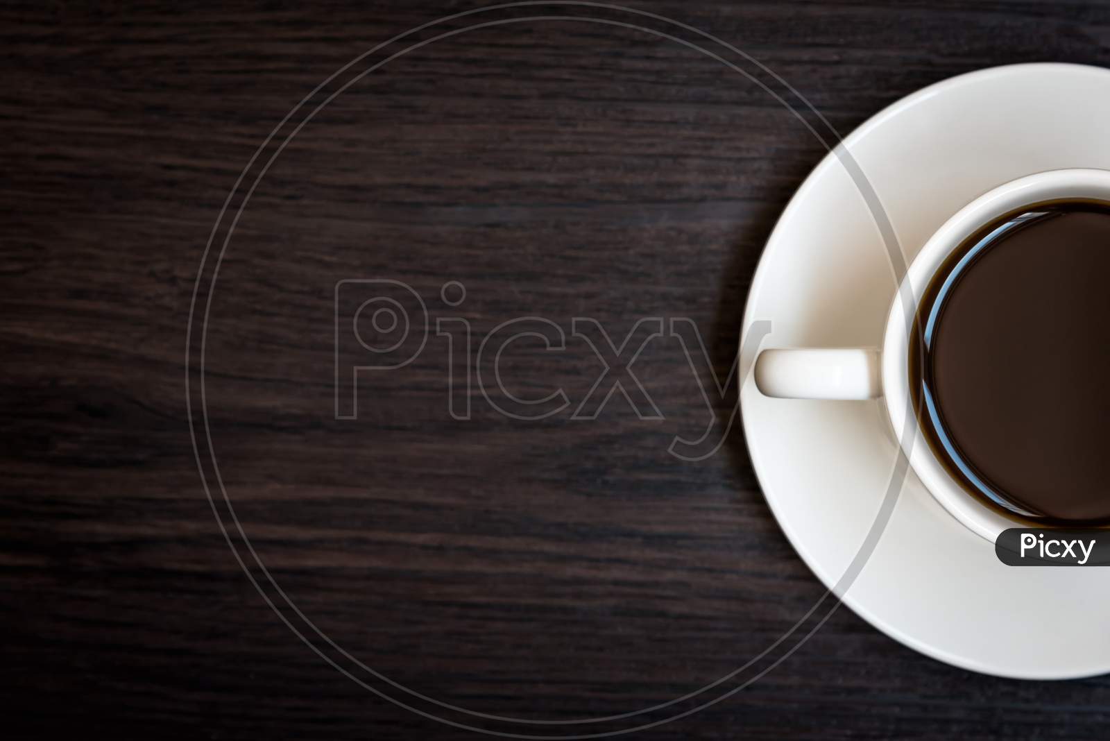 White Coffee Cup On Wood Table Background With Copy Space, Half Cup With Full Of Coffee, Dark Tone Still Life And Vignette, Top View For Advertisement, Business And Drinking Concept, Relax Concept