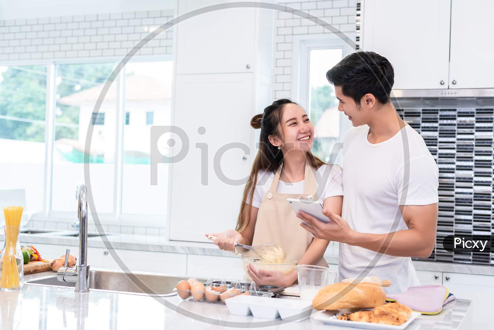 Asian Couples Cooking And Baking Cake Together In Kitchen Room At Home. Love And Happiness Concept Sweet Honeymoon And Valentine Day Theme