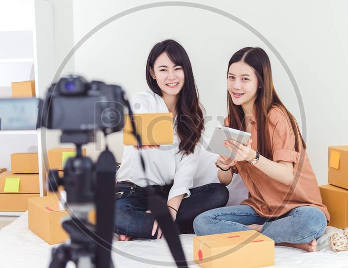 Two Asian Women Using Digital Video Camera For Recording And Presenting New Product Advertisement. Vlog And Influencer Concept. People Part Time Job And Occupation. Young Teenagers Using Technology