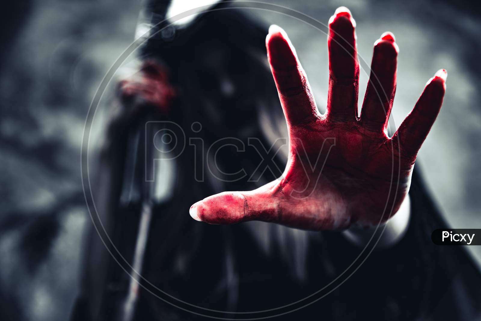 Witch Showing Bloody Hand With Reaper. Female Demon Angel In Black Clothes And Hood On Grunge Wall Background. Halloween Day And Mystery Concept. Fantasy Of Magic Theme. Afterlife And Death Concept.