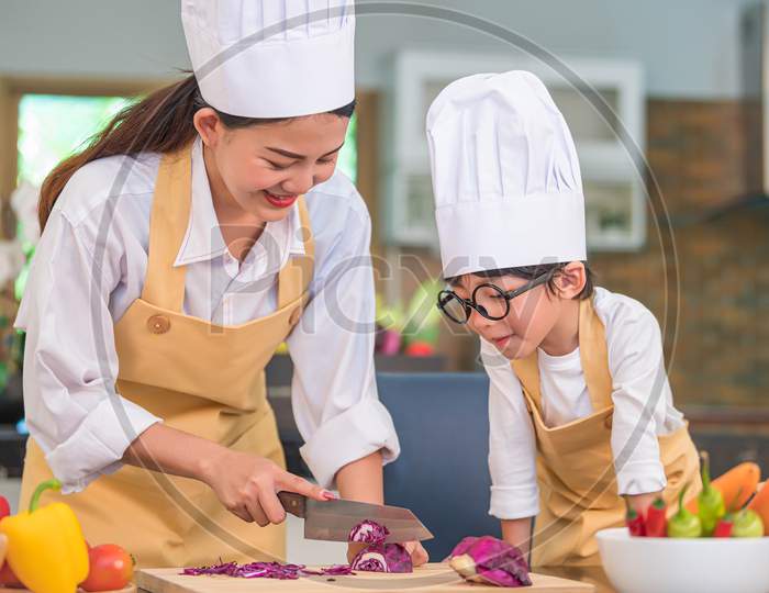 Happy Beautiful Asian Woman And Cute Little Boy With Eyeglasses Prepare To Cooking In Home Kitchen. People Lifestyles And Family. Homemade Food And Ingredients Concept. Two Thai People Life