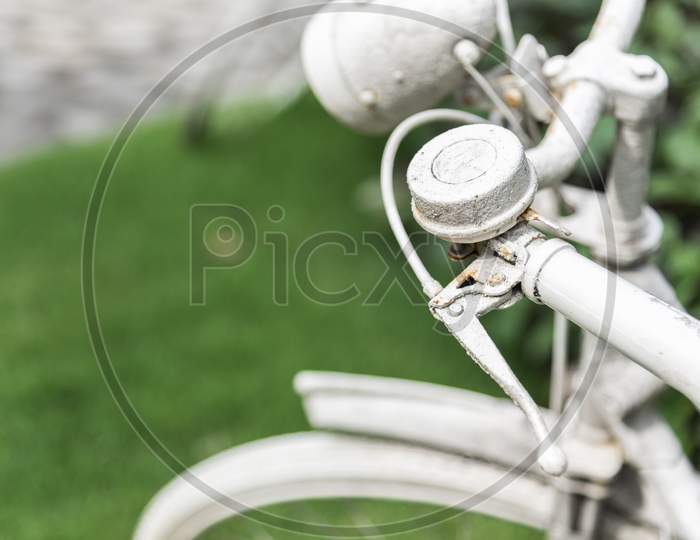White Bicycle In Garden Background. Vintage And Nature Concept. Close Up And Bike Handle.
