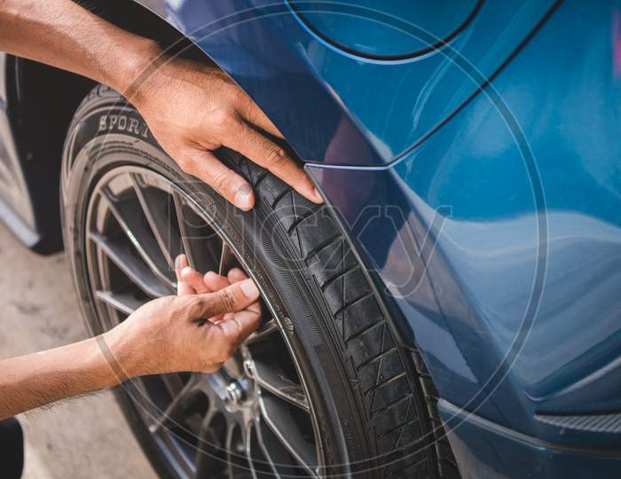 Closeup Male Automotive Technician Removing Tire Valve Nitrogen Cap For Tire Inflation Service At Garage Or Gas Station. Car Annual Maintenance And Repair Concept. Safety Road Trip And Travel Theme.