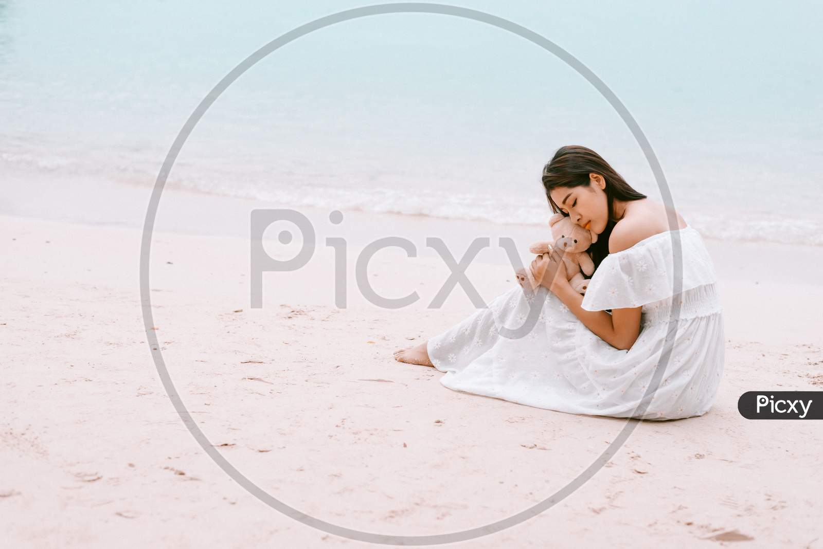 Asian Woman Hug Bear Doll And Waiting For Love That Make Her Happy At Beach. Lonely And Beauty Concept. Back View Scene Of Girl. Ocean And Sea Theme. Copy Space In Left Side. Soulmate Theme.